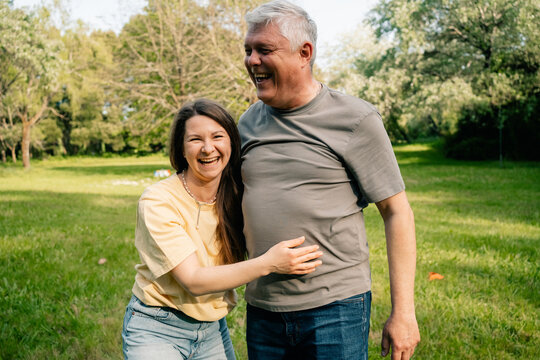  Two people laughing together in sunny green park
