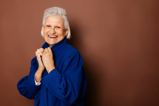 Stylish senior woman smiling and holding her blue coat