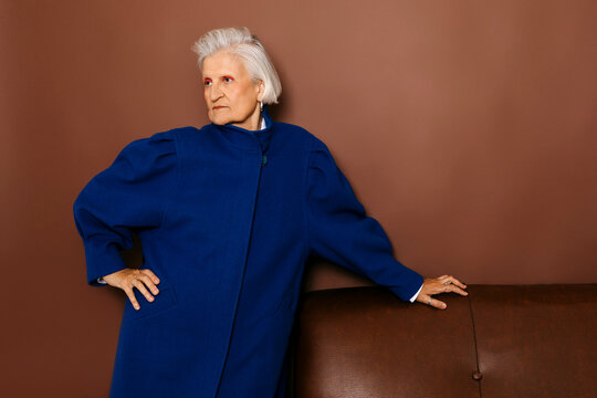 Senior fashion model posing with blue coat and hand on hip