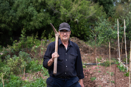 Senior farmer holding pickaxe on shoulder