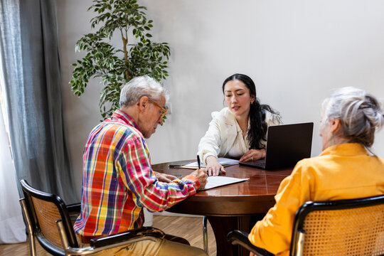 couple meeting with financial advisor at office signing document