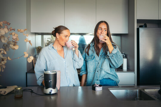 Women having smoothies in the kitchen in the morning