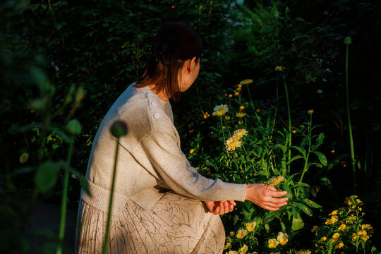 An Asian woman appreciating flowers in the sunset.