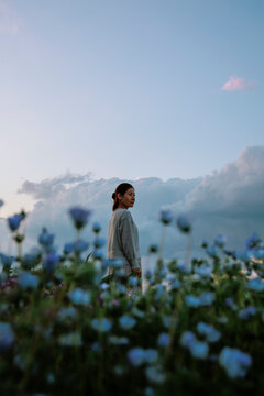 A blue dreamscape: a contemplative woman in a field of flowers.