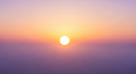 A blurred beautiful sunrise with soft pastel colors painting the sky and a hazy horizon.