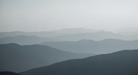 Layered mountain ranges fade into a hazy, atmospheric sky, creating a serene and expansive landscape.
