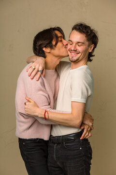 One man in an interracial gay couple kisses the other on the cheek
