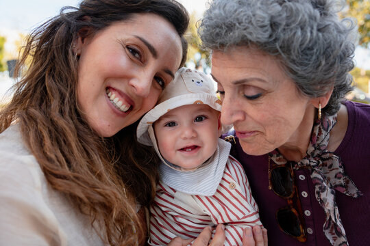 Mother and grandmother embracing baby 