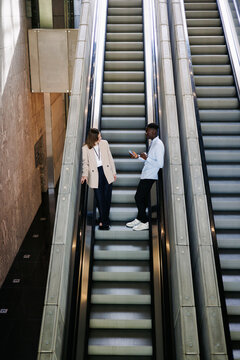 Two Professionals Chatting on Escalators