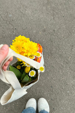 Bright flowers in a reusable tote bag held by anonymous person