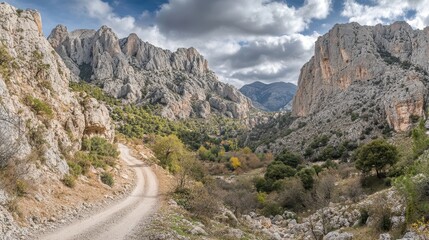 A Winding Mountain Road Through a Rocky Valley Under Dramatic Clouds