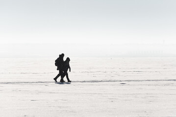 Silhouettes In Snow. Two Shadowed Figures Move Gently Over Expansive White Snowfield Amid Quiet Serenity