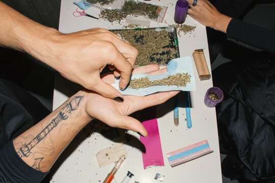 hands putting marijuana rolling paper joint 