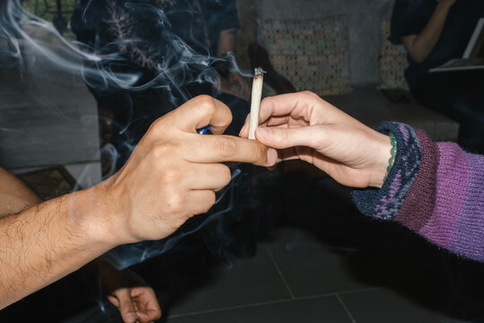 Hands passing lit joint social sharing