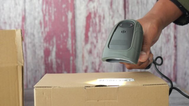 Close up of person scanning barcode on cardboard box using digital reader for parcel delivery service