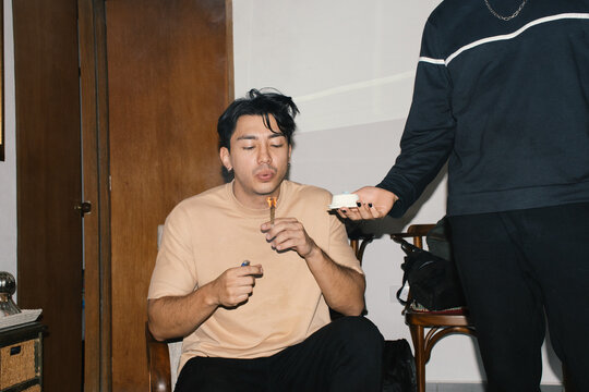 man lighting joint while friend holds ashtray 
