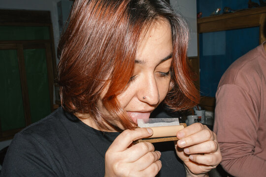 woman licking rolling paper preparing join

