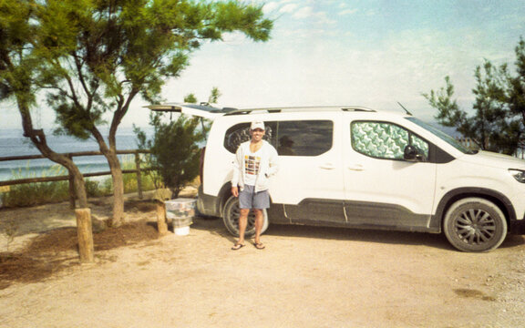 Man in front of his minivan on a beach in Portugal