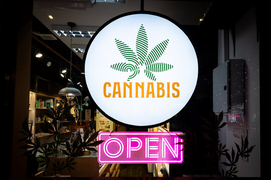 A neon pink open sign on a cannabis shop in Thailand
