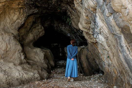 A woman exploring the entrance of a sea cave.