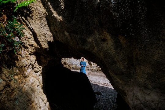 A woman lost in deep thought before a sea cave.