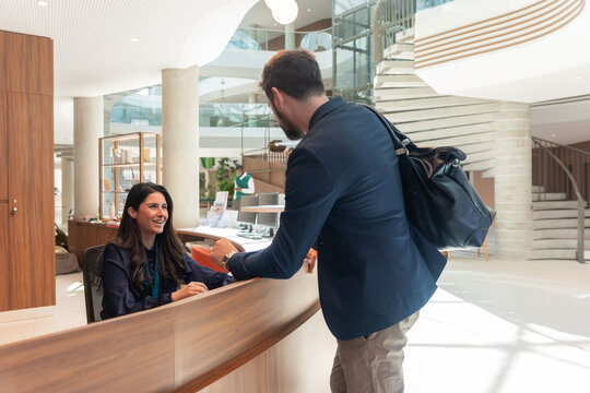 Man Talking To Receptionist In Office Entrance.