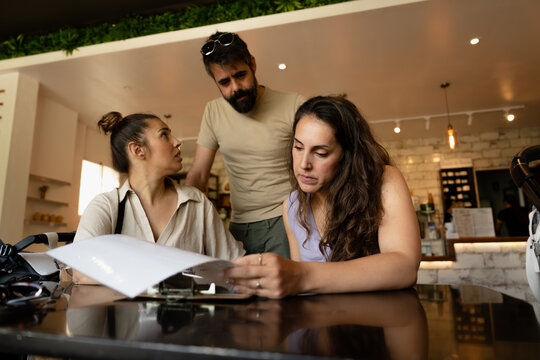 three people looking at the breakfast menu at a coffee shop
