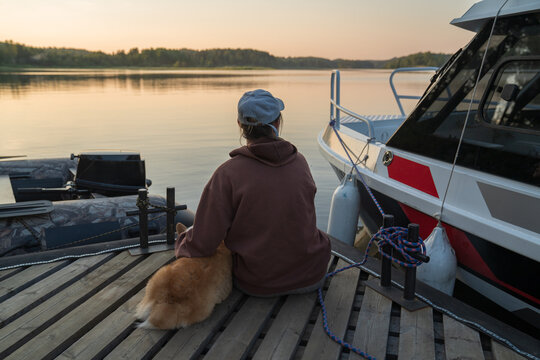 Person Sitting on Dock with Dog at Sunset