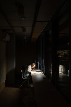 Focused Work Under Desk Lamp at Night