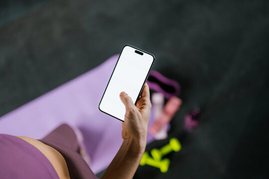 A woman uses white-screen mobile phone in the gym