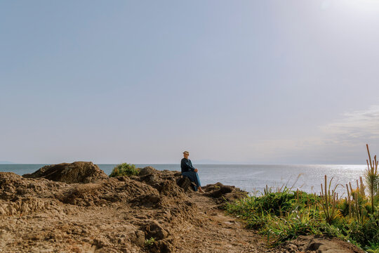 A woman relaxing on seaside rocks.