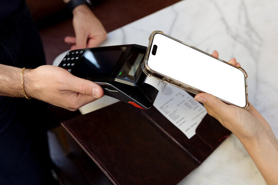 Young woman paying the bill in a restaurant using a mobile phone
