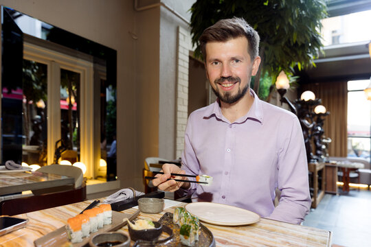 A young man is eating sushi in a restaurant