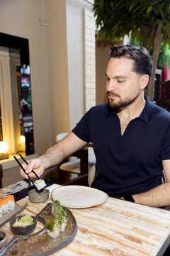 A young man is eating sushi in a restaurant