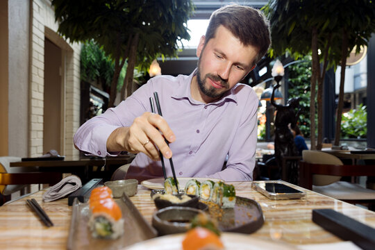 A young man is eating sushi in a restaurant