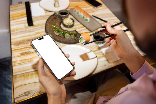 A young man is eating sushi in a restaurant