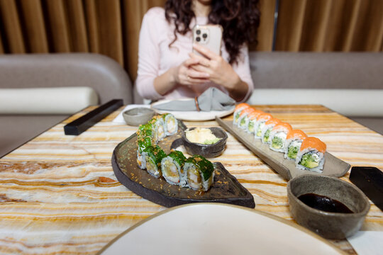 young woman taking pictures of rolls in a restaurant
