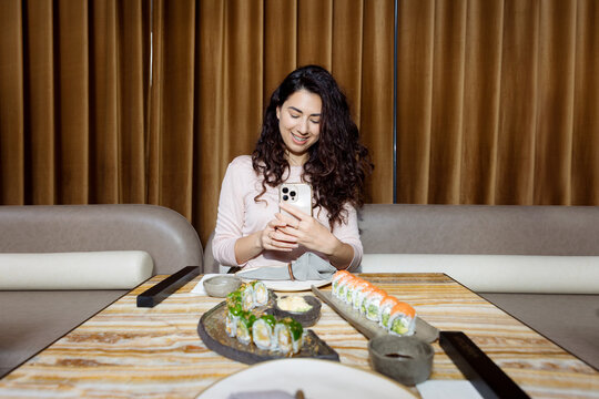 young woman taking pictures of rolls in a restaurant