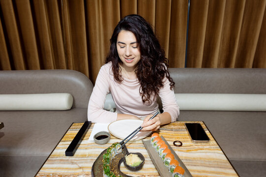 Young woman with braces eating sushi