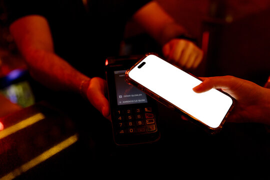 Young woman paying the bill in a restaurant using a mobile phone