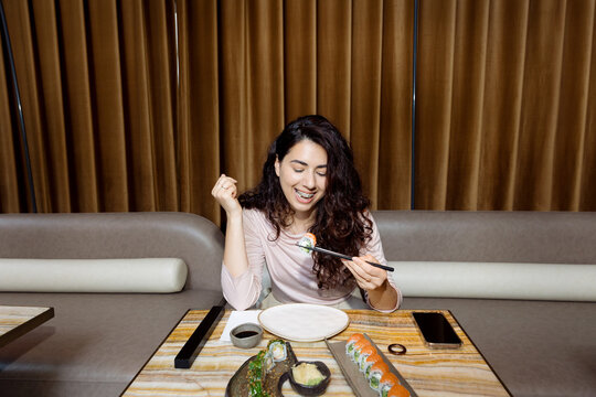 Young woman with braces eating sushi
