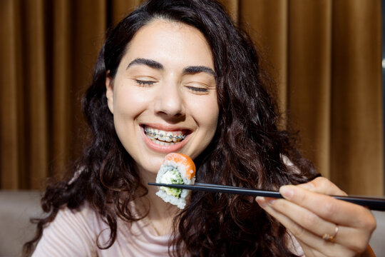 Young woman with braces eating sushi