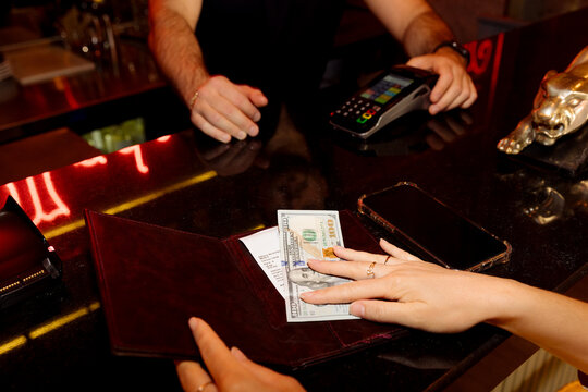 A young woman pays a bill in a restaurant