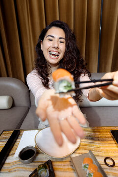 Young woman with braces eating sushi