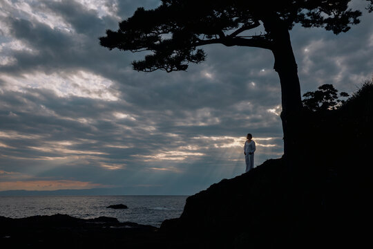 A woman admiring God rays at the seaside.