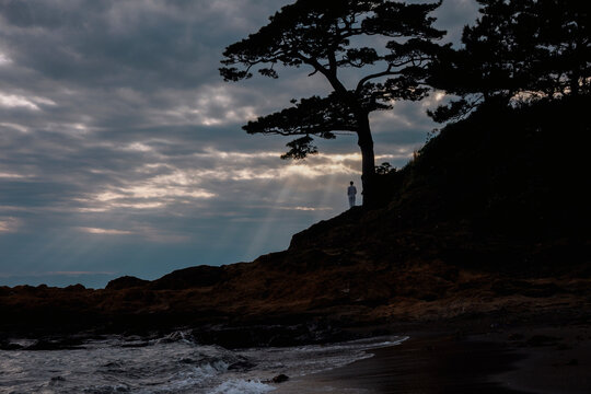 A woman admiring God rays at the seaside.