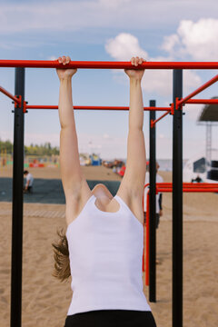 Person Hanging on a Pull-Up Bar at an Outdoor Fitness Park