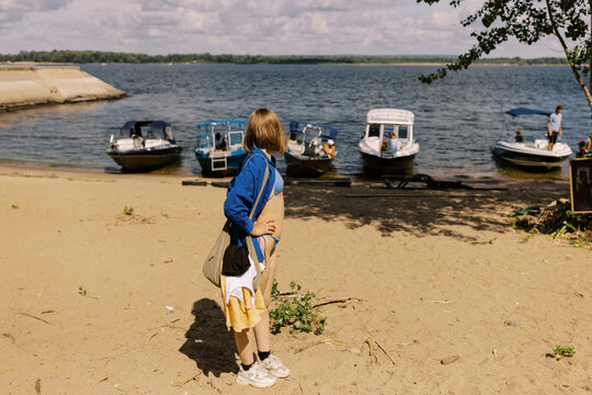 Woman Observing Boats Parked by a Scenic Beach on a Sunny Day