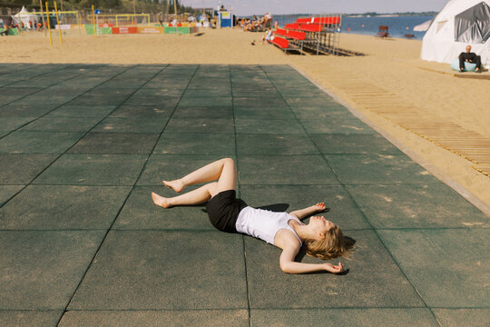 Young Woman Relaxing Outdoors on a Sunny Day by the Playground