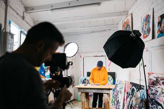 Artist drawing at table under studio lights

